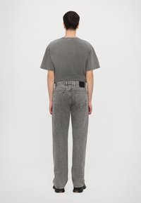 Gray cotton T-shirt with short sleeves, paired with high-waisted, straight-leg gray jeans featuring a black label on the back waistband.