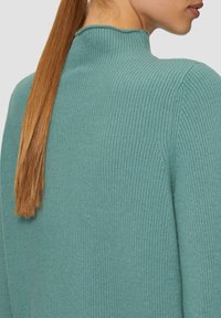 Geribbelde, hoge hals trui van zacht teal stof; heeft een gestructureerde afwerking en een aansluitende pasvorm met een smalle kraag.