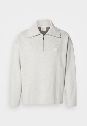 Világosszürke pulóver cipzáros előlappal és széles gallérral. Kis négyzet alakú logó található a mellkason. Texturált anyagból készült.