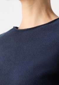 Top lavorato a maglia blu navy con scollatura rotonda e maniche corte, caratterizzato da una texture morbida e una finitura liscia.