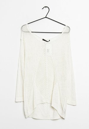 Hvid strikket langærmet sweater med et diamantmønster, hængende på en sort bøjle mod en hvid baggrund.