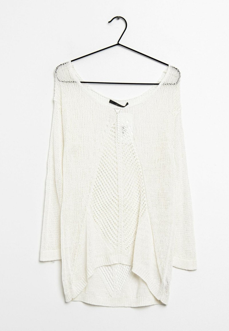 Pull blanc en maille à manches longues avec un motif en losange, suspendu à un cintre noir sur un fond blanc.