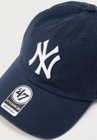 Μπλε ναυτικό καπέλο baseball με λευκό κεντημένο λογότυπο NY, ρυθμιζόμενο λουράκι και υφή υφάσματος. Διαθέτει ετικέτα της μάρκας στη βρύση.