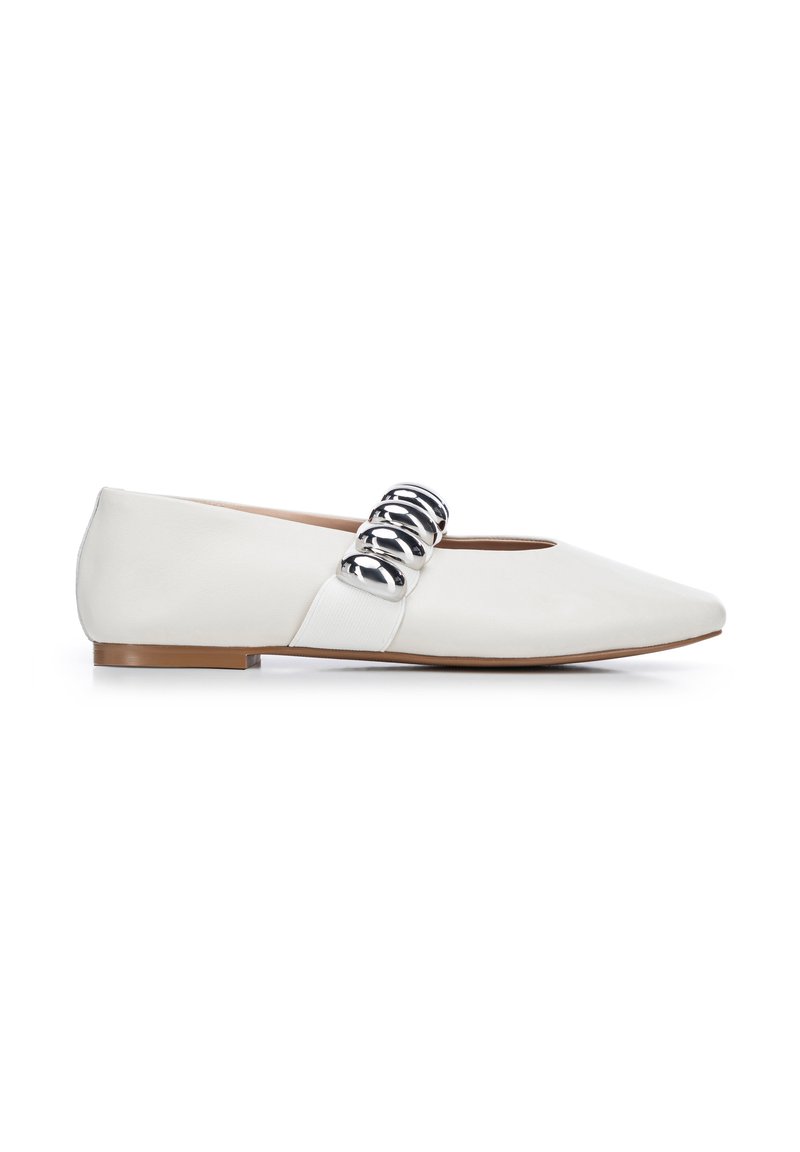Zapatos planos blancos con punta afilada, que presentan un acento de cadena plateada brillante y una textura de cuero suave. Suela marrón, diseño minimalista.