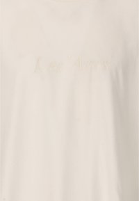 Vit bomull T-shirt med den emblemerade texten "Les'Arcs" i en subtil krämfärg. Mjuk textur med en klassisk rundad halsdesign.