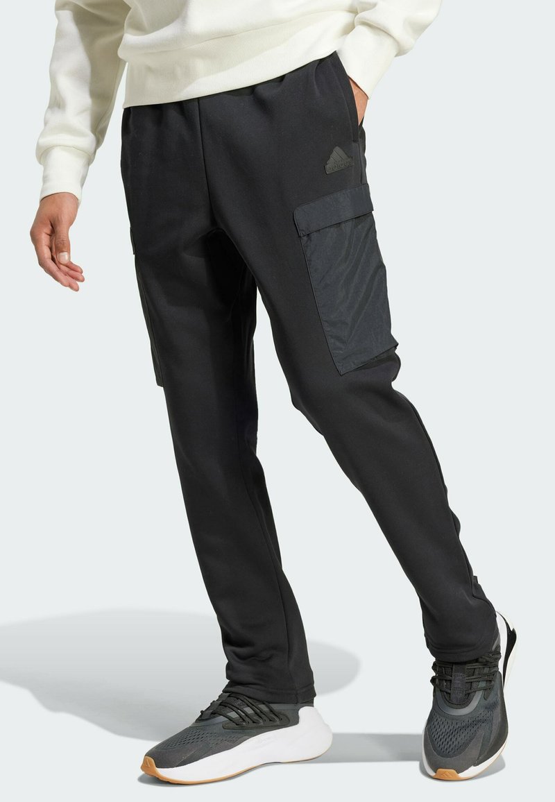 Black athletic pants featuring cargo pockets, a smooth texture, and an elastic waistband, paired with grey and white sneakers.