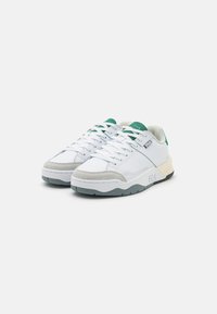 Scarpe atletiche bianche con dettagli verdi, dotate di una tomaia in pelle e tessuto, suola in gomma e un logo del marchio ben visibile sul lato.