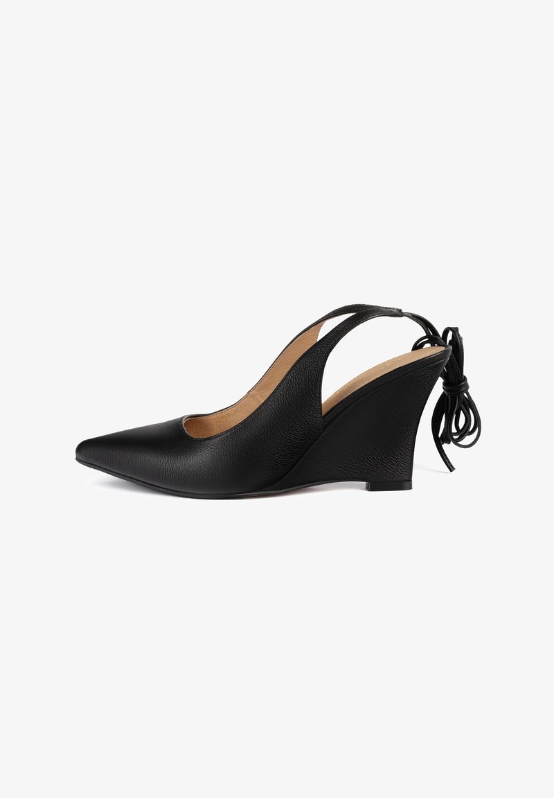 Chaussure compensée en cuir noir à bout pointu, bride arrière, talon de hauteur moyenne et détail de nœud noué à l’arrière.