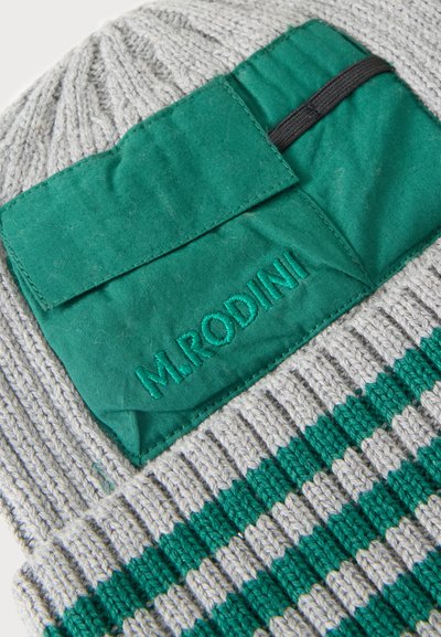 Tissu tricoté gris et vert avec une poche en tissu verte brodée de "M.RODINI" et une boucle élastique noire attachée.
