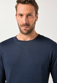 Dunkelblaues Langarmshirt mit rundem Ausschnitt, aus weichem Baumwollstoff gefertigt, mit minimalen Nähten und glatter Textur.