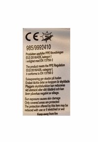 Etiketten har et lyst stof med trykt tekst i sort, herunder sikkerhedsadvarsler, bestemmelser og plejeinstruktioner.