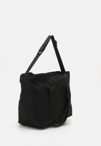 Saco tote preto feito de nylon, com alças ajustáveis e detalhes do logótipo. Design suave e estruturado com um interior espaçoso.
