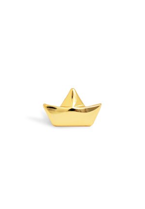 Petit objet doré brillant en forme de bateau en papier sur un fond blanc uni.
