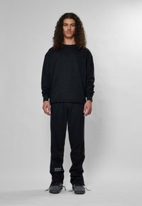 Felpa nera e pantaloni abbinati realizzati in tessuto morbido. Presentano una vestibilità rilassata, polsini elasticizzati e un logo discreto sui pantaloni.