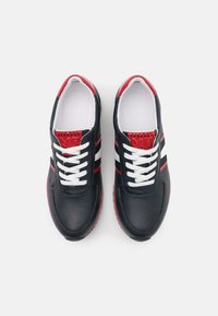 Zapatillas negras perforadas con acentos rojos y franjas blancas. Cuentan con cordones blancos, puntera redonda y un diseño elegante.