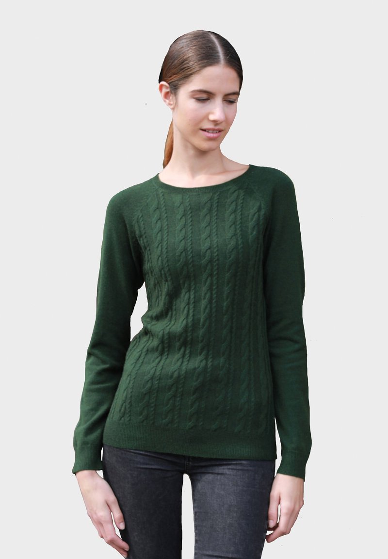Pull en maille torsadée vert avec des manches longues, un col rond et un ourlet côtelé. Fabriqué dans un tissu doux et texturé. Porté sur un jean noir.