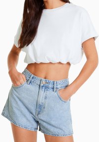 Vit kortärmad t-shirt i bomull, kombinerad med ljusblå denimshorts med hög midja, bälteshällor och framfickor.