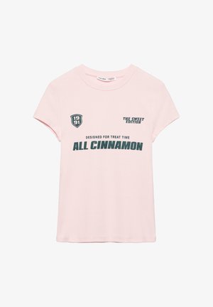 Svijetloružičasta majica kratkih rukava s tamnozelenim natpisom "ALL CINNAMON", "THE SWEET EDITION", "DESIGNED FOR TREAT TIME" i grbom s natpisom "1991".