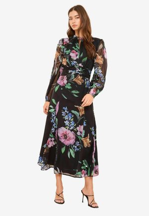 Must lilleline kleit pikkade läbipaistvate varrukatega ja vormis vöökohaga. Omaduses on erksad roosad, sinised ja rohelised lilled voolavas kangas.