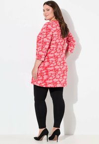 Kwiatowa tunika w intensywnym czerwonym kolorze z rękawami trzyczwartowymi, w parze z czarnymi legginsami i spiczastymi szpilkami. Gładki materiał, luźny krój i okrągły dół.