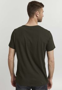 Olivengrønn t-skjorte med korte ermer og rund hals, laget av bomullsstoff, med rett snitt og minimale sømmer.