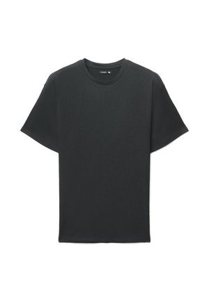 T-shirt nera a maniche corte in tessuto strutturato, con scollo rotondo e vestibilità comoda. Nessun logo o dettaglio visibile.