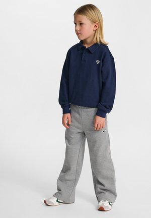 Marineblaues Langarm-Polohemd mit Kragen, kombiniert mit hellgrauen Jogginghosen. Beide Kleidungsstücke haben ein besticktes Logo. Lässige Schuhe.