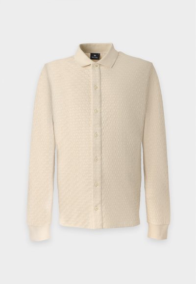 Chemise beige à manches longues avec boutons, motif texturé, col plié et poignets côtelés, présentée sur un fond uni.