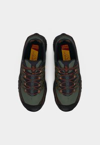 Πράσινα και μαύρα αθλητικά παπούτσια με υφασμένο επάνω μέρος, πορτοκαλί λεπτομέρειες και περίπλοκο σύστημα κορδονιών. Λαστιχένια σόλα για καλύτερη πρόσφυση.