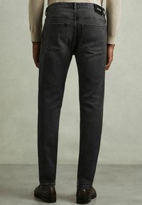 Vaqueros de mezclilla de un gris oscuro con un corte ajustado, que cuentan con una cinturilla alta, dos bolsillos traseros y sutiles detalles de costura.