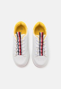 Sneaker bianche con fodera interna gialla, dettagli a righe multicolori e allacciatura tradizionale con forature sulla punta.