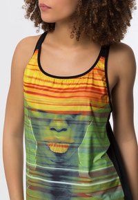 Mouwloze tanktop van lichte stof, met een kleurrijke abstracte print van een gezicht met horizontale strepen in groen, oranje en geel.