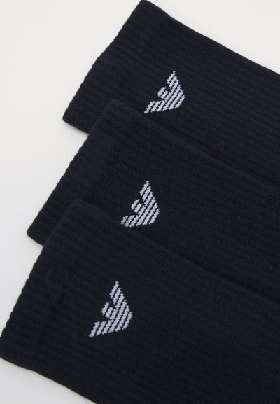 Mornarji modri rebrasti nogavice z belim črtastim logotipom. Oblikovanje vključuje standardno dolžino za posadko in teksturirano tkanino.