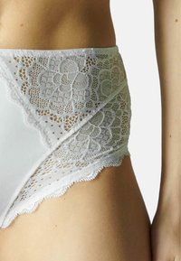 Witte hooggesneden onderbroek met een kantaccent. Zachte stof, bloemenkantpatroon en gegolfde randen versterken de textuur en visuele details.