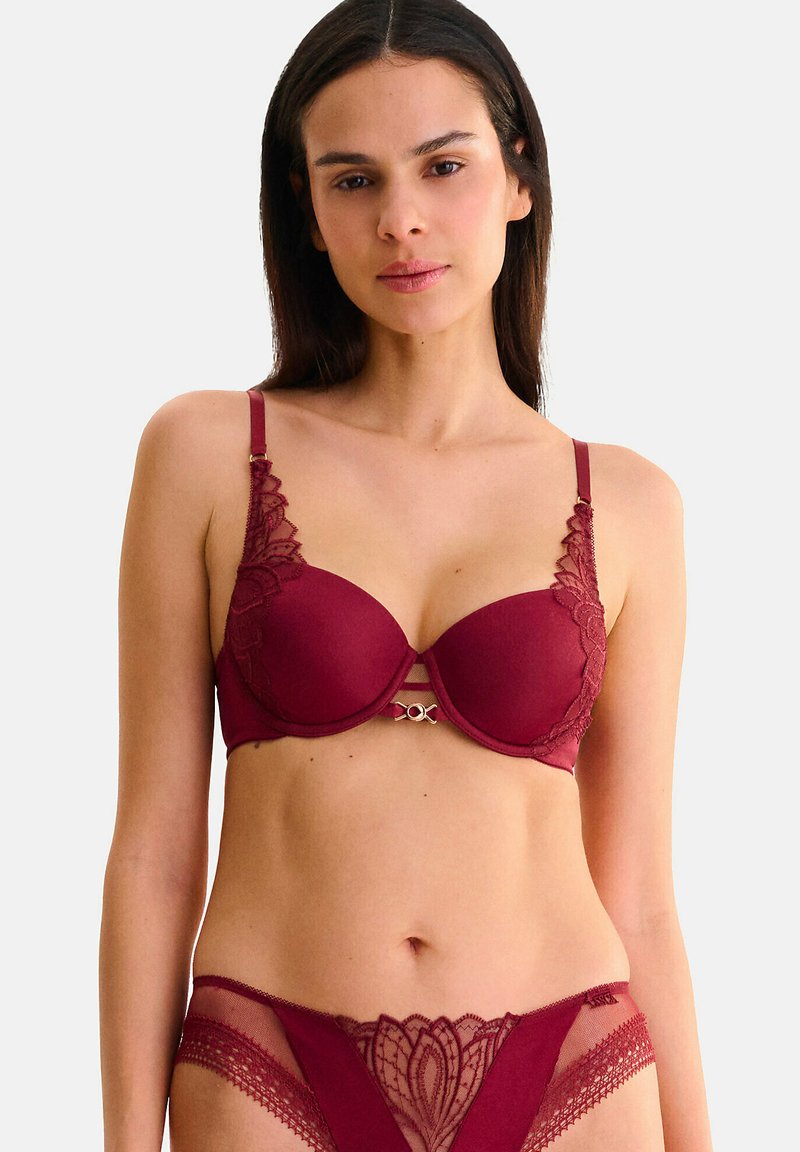 Soutien-gorge en velours bordeaux avec des détails en dentelle, bretelles ajustables et un accent en métal doré décoratif ; culottes en dentelle transparente assorties avec un motif floral.