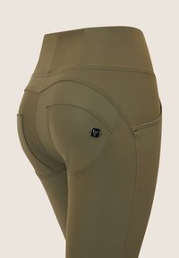 Leggings verde oliva realizzati in tessuto liscio, con cuciture curve, due tasche posteriori e un piccolo logo sulla destra.