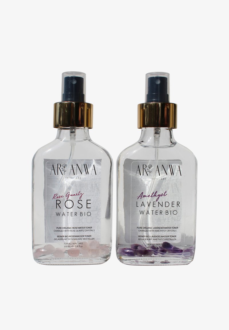 Deux flacons vaporisateurs transparents de toniques d'eau de soin ARANWA ; l'un Rose Quartz Rose, l'autre Améthyste Lavande, avec des cristaux au fond.