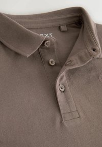 Barna, texturált anyagból készült galléros póló, három gombbal és diszkrét márkajelzéssel a mellrészen.