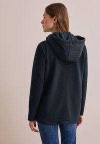 Marinblå huva jacka med en mjuk textur, som har en quiltad huva, långa ärmar och en subtil logotypdetalj på armen.