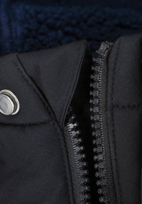Black jacket fabric with a zipper and snap closure. Features a textured lining visible behind the collar. Zipper is raised with a track design.