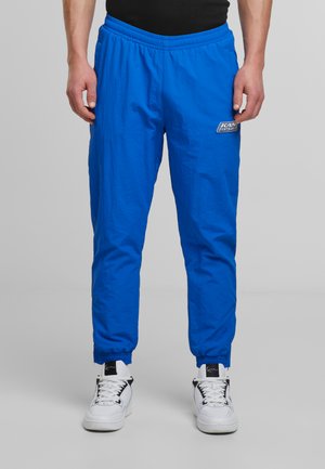 Blue sports pants with an elastic waistband, cuffed ankles, and a small logo patch. Made of lightweight fabric with a smooth texture.
