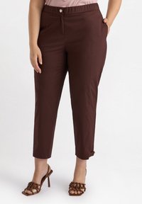 Bruna cropped byxor med en slät textur, med knappstängning och sidofickor. Matchas med bruna sandaler med klack och remmar.