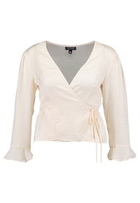Krämfärgad blus med lång ärm, knytdetalj vid midjan, v-ringning, mjuk textur och utsvängda manschetter. Topshop-logotyp synlig.