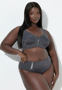 Szary biustonosz typu bralette i pasujące majtki z wysokim stanem wykonane z gładkiej tkaniny. Posiadają cienkie ramiączka i satynowe akcenty po bokach.
