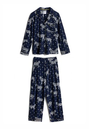 Chemise bleu marine avec des pois jaunes, motifs zèbre, liseré jaune, fermeture par boutons et poche poitrine.