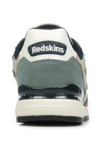 Sneaker vert et beige avec un talon blanc et marine, arborant un logo à l'arrière, une semelle en caoutchouc, une texture en suède et des accents en maille.