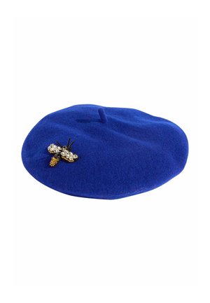 Blue felt beret featuring a metallic bee brooch with crystal accents and a yellow body. Rounded, soft texture with a top tab detail.