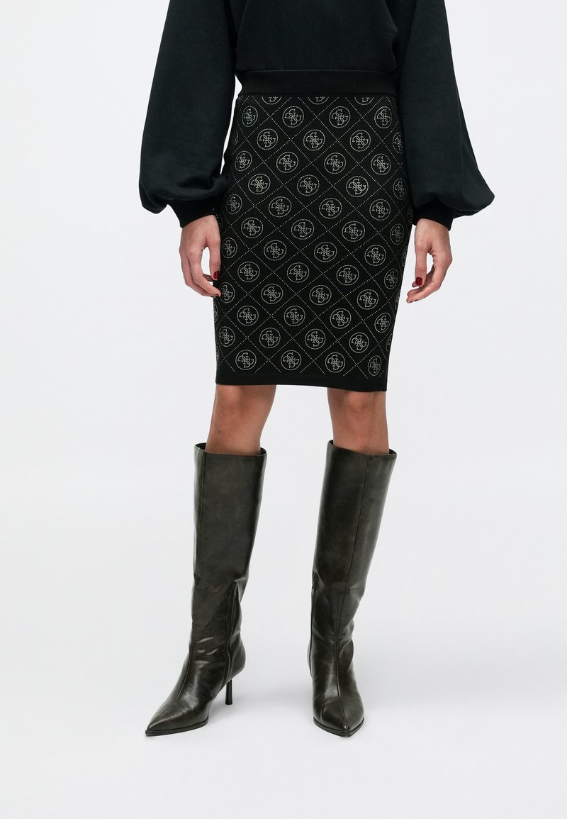 Schwarzer Bleistiftrock mit Diamantmuster und Logoakzenten, kombiniert mit kniehohen dunklen Lederstiefeln mit Absatz.