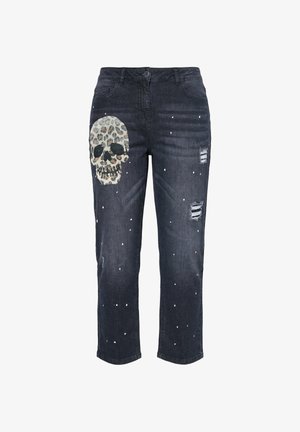 Jeans negros desgastados con salpicaduras de pintura blanca y un gran gráfico de calavera con estampado de leopardo en el muslo izquierdo.