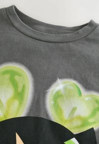 Grå bomulds t-shirt med et grafisk design med to grønne hjerteformer, der fremhæver en glat tekstur og rund halsudskæring.